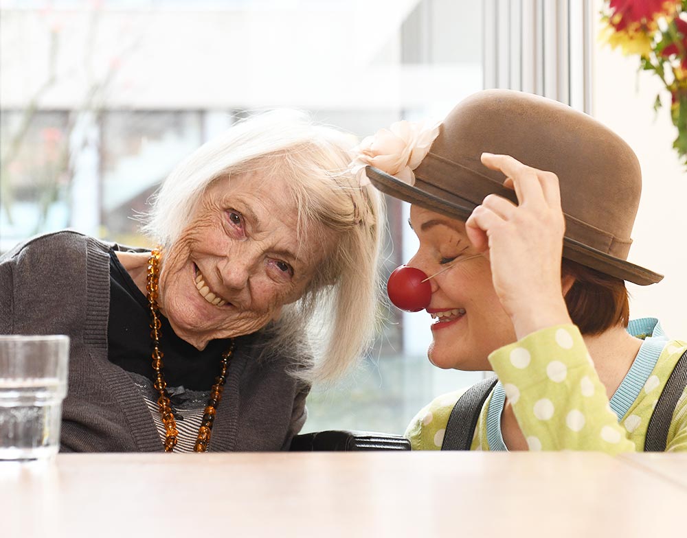 Gesichter einer älteren lachenden Dame und eines Clowns